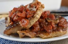 two pieces of meat covered in tomato sauce on top of a white and blue plate