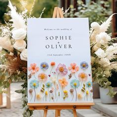 an easel with flowers on it and a sign that says, welcome to the wedding of sophiie and olliver