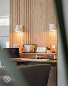 a laptop computer sitting on top of a wooden desk next to a lamp and chair