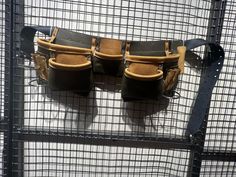 three leather seats sitting on top of a metal cage next to each other in front of a white wall