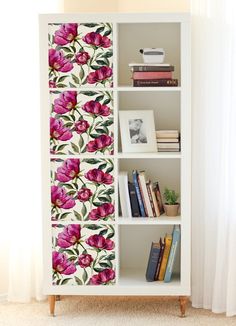 a white book shelf with pink flowers on it and bookshelves in the background