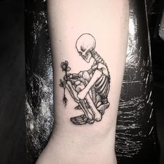 a black and white tattoo of a skeleton sitting on a bench with a flower in its hand