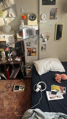 an unmade bed in a cluttered room with many pictures on the wall and floor