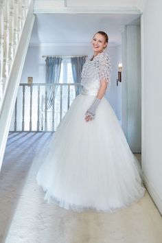 a woman in a white wedding dress is standing by the stairs and smiling at the camera