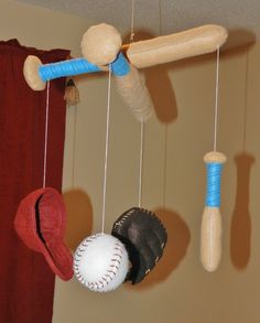 three baseballs, a bat, and a ball hanging from strings in a room