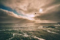 an airplane is flying over the ocean on a cloudy day with some clouds in the sky