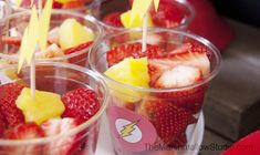 several cups with strawberries and pineapples in them