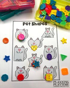 the printable cat shape matching game is shown next to some plastic buttons and scissors