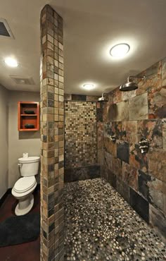 a bathroom with a toilet, shower and stone tile wall in the middle of it