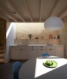 a kitchen with a white table and blue chairs next to a brick wall in the background