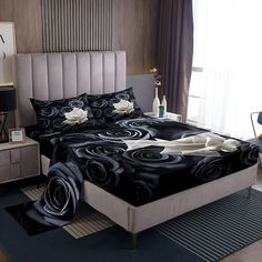 a bed with black and white roses on it in a room next to a window