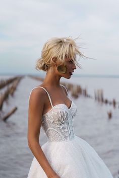 a woman in a wedding dress standing by the water