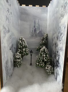 a snow scene with trees and a street light in the middle is shown through an open door