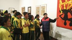 a group of people standing next to each other in front of paintings on the wall