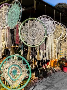 there are many circular objects hanging on the wall together in this shop window, and they have tassels attached to them