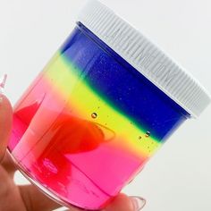 a person holding a cup with colored liquid in it's bottom and the lid partially open