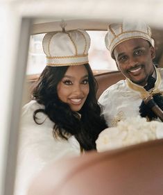 a man and woman sitting in a car wearing crowns on their heads, smiling at the camera