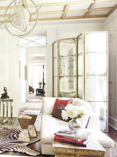 a living room filled with furniture and a white couch in front of a mirror on the wall