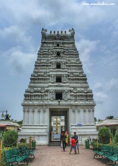 two people are standing in front of the entrance to a large temple with green benches