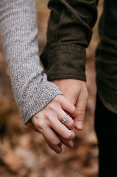 two people holding hands while walking in the woods