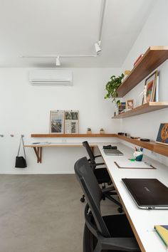 an office with a desk, laptop and bookshelf on the wall next to it