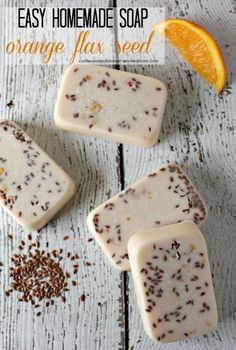 three bars of soap sitting on top of a wooden table next to an orange slice