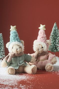 two teddy bears sitting next to each other in front of snow covered trees and red wall