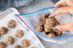 a person holding a plastic bag filled with meatballs next to a tray of doughnut holes