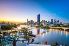 the city skyline is lit up at sunset in this beautiful photo from across the river