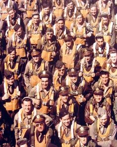 a large group of men dressed in uniforms and hats posing for a photo with their arms around each other