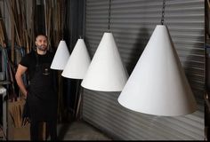 a man standing next to three white lamps