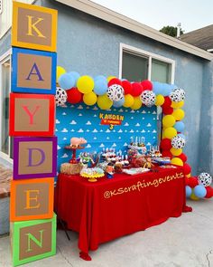 a birthday party with balloons, cake and decorations on the outside of a house in front of a blue building