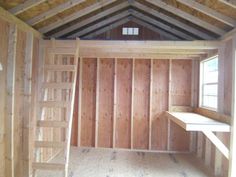 an empty room with wooden walls and ladders to the loft, in front of a window