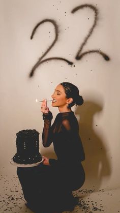 a woman sitting on the floor with a cake in front of her and numbers drawn on the wall behind her