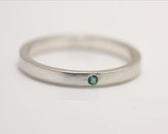 One petite 1.75 mm emerald is flush set in sterling silver in this striking minimalist ring. It can be worn by itself or as an accompaniment to another ring, as in the third photo, where it is paired with a white sapphire ring (see listing on my Etsy page).  This ring would make a beautiful engagement or wedding ring. This ring also works well as a stack ring.Please allow up to 3 weeks processing time for filling your order.Please contact me for information if you are not clear on how to measure Modern Sterling Silver Birthstone Ring For Everyday, Minimalist Silver Stackable Rings With Tension Setting, Minimalist Stackable Emerald Cut White Gold Rings, Minimalist Stackable White Gold Emerald Cut Rings, Minimalist Emerald Cut Stackable Rings, Minimalist White Gold Stackable Rings With Emerald Cut, Everyday Minimalist Emerald Cut Ring, Modern Stackable Emerald Ring For Anniversary, Minimalist Emerald Stackable Promise Rings