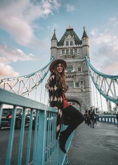 a beautiful woman standing on top of a bridge next to a tall tower with a sky background