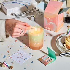 a person lighting a candle on top of a table next to some cupcakes