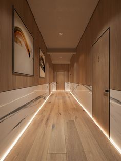 an empty hallway with wood flooring and white painted wall art on the walls behind it