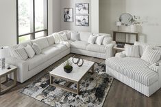 a living room filled with white couches and pillows on top of a wooden floor