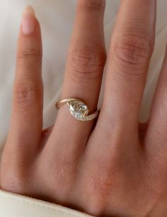 a woman's hand with a diamond ring on top of her finger and white cloth