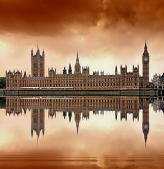 the big ben clock tower towering over the city of london in england, reflected in the water