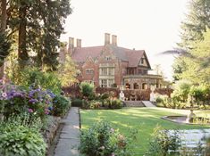 a large brick house surrounded by trees and flowers