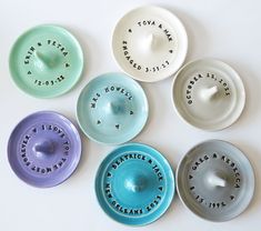 five ceramic bowls with words on them sitting next to each other in different colors and sizes