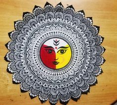 an intricately designed wall hanging on the side of a wooden door with a face painted in red, yellow and white