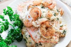 a white plate topped with meat covered in sauce and shrimp next to broccoli