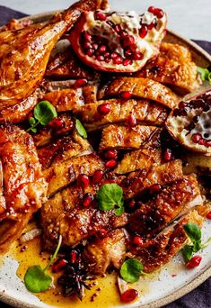 a white plate topped with meat covered in pomegranate and garnish