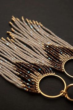 two pairs of gold and silver beaded earrings on a black surface with beads hanging from them