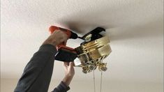 a person using a drill to fix a ceiling fan