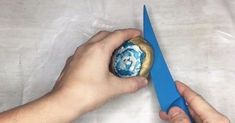 a person holding a blue pair of scissors in their hand