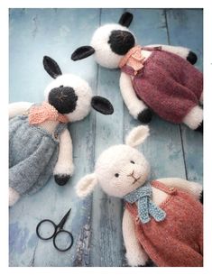 three stuffed animals sitting on top of a wooden floor next to scissors and yarns